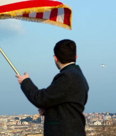 A seminarian at the Pontifical North American College waves an American flag as the helicopter carrying Pope Benedict passes by